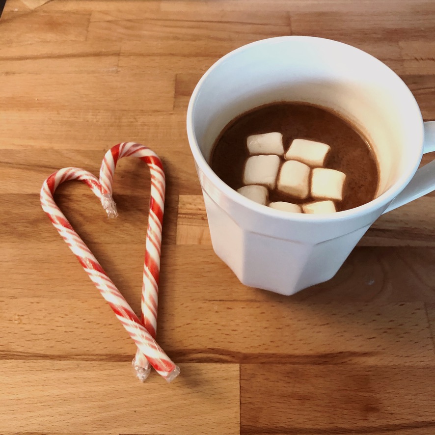 A cup of hot chocolate and heart shaped candy canes. 