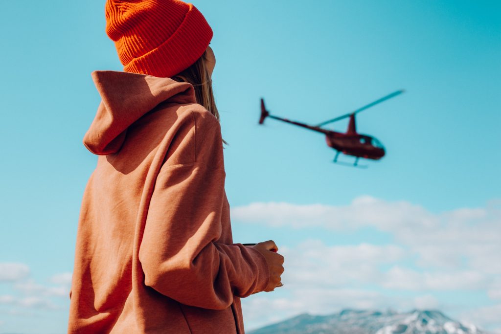 A woman watching a helicopter flying. 