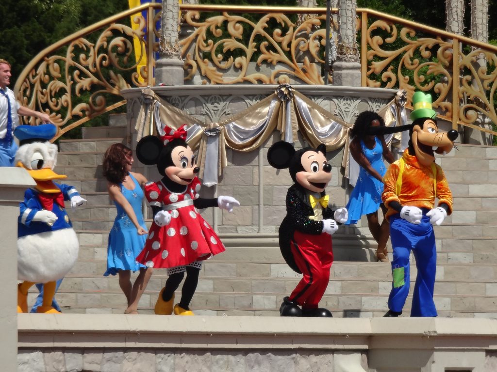 Mickey Mouse, Minnie Mouse, Goofy, and Donald Duck dancing in front of Cinderella's Castle at Disney World, Orlando, FL.