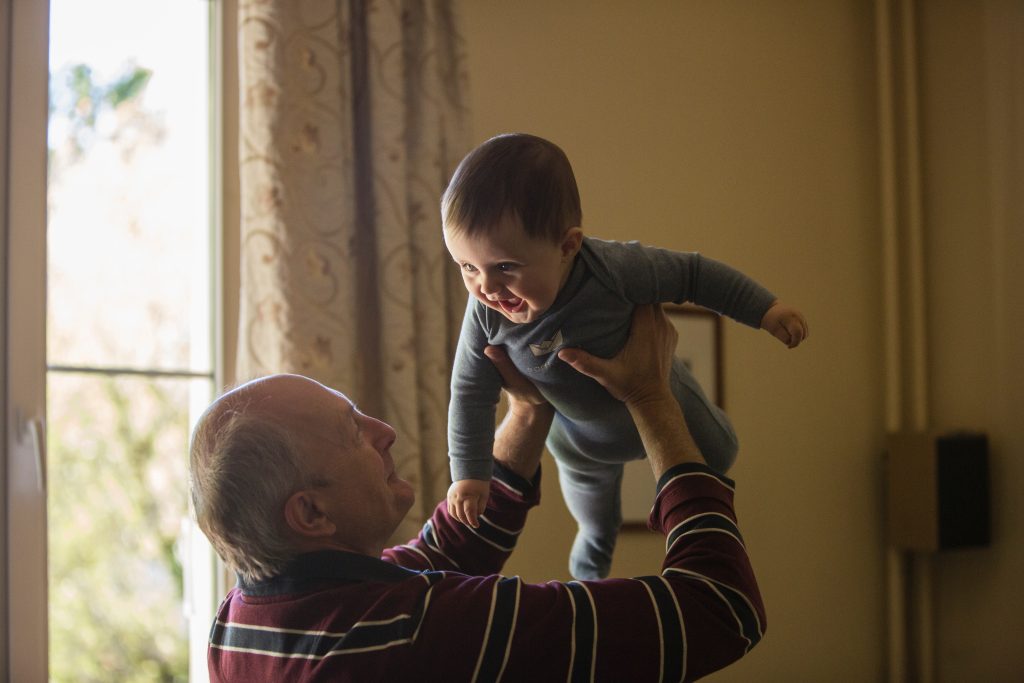 Grandpa holding grandson in the air. Multigenerational vacation tips - Creates lifelong memories.