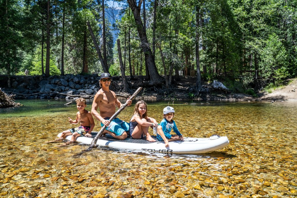 Father and three kids on a paddle board.