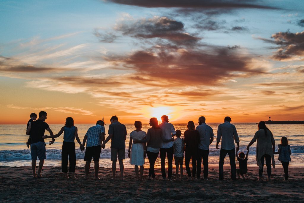 Multigenerational family on the beach at sunset. (Multigenerational vacation tips)