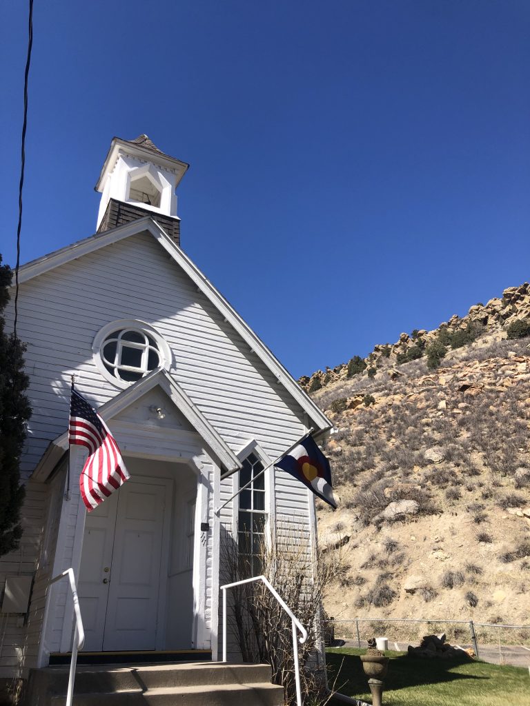 Historic little white church in Morrison CO with the mountains in the background. 